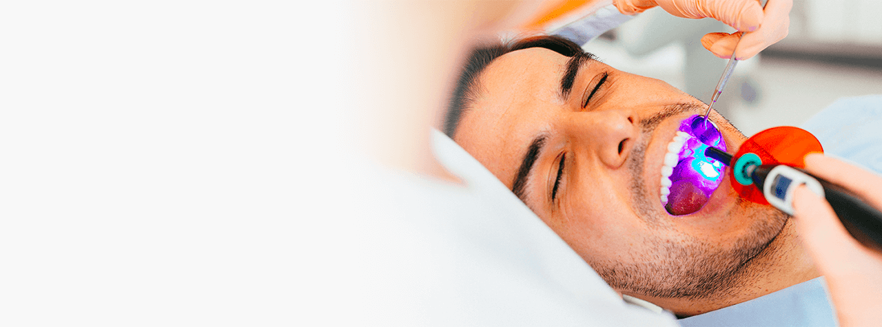 A dental professional wearing safety PPE gear and white lab coat smiling compassionately